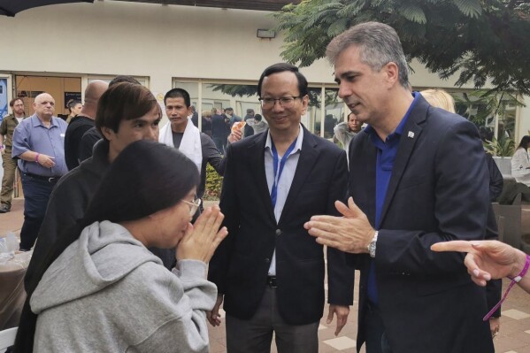 In this photo provided by Thailand's Foreign Ministry, Israel's Foreign Minister Eli Cohen, right, talks to one of the freed Thai hostages at the Shamir Medical Center in Israel Saturday, Nov. 25, 2023. Hamas freed 10 Thai nationals seized in the group's surprise attack on southern Israel last month, releasing them alongside Israeli hostages who were part of the first swap under a new cease-fire deal. (Thailand's Foreign Ministry via AP )