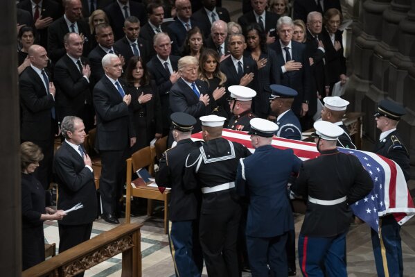 
              The flag-draped casket of former President George H.W. Bush is carried by a military honor guard past former President George W. Bush, President Donald Trump, first lady Melania Trump, former President Barack Obama, Michelle Obama, former President Bill Clinton, and former Secretary of State Hillary Clinton, at the conclusion of a State Funeral at the National Cathedral, Wednesday, Dec. 5, 2018, in Washington. In the second row are Vice President Mike Pence, and his wife Karen Pence, former Vice President Dan Quayle, and his wife Marilyn Quayle and former Vice President Dick Cheney. (AP Photo/Carolyn Kaster)
            