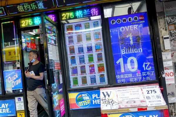 An electronic sign hanging at a convenience store announces a Powerball jackpot exceeding 1 billion dollars as a man leaves the store with his lottery tickets, Wednesday, July 19, 2023, in New York. The new jackpot for Wednesday’s Powerball drawing would be the seventh highest in U.S. history and the third largest for the game. (AP Photo/Mary Altaffer)