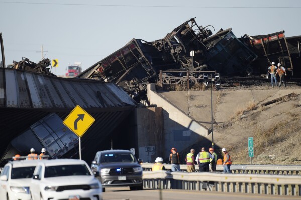 Workers toil to clear cars that derailed in an accident over Interstate 25 northbound, Monday, Oct. 16, 2023, north of Pueblo, Colo. (AP Photo/David Zalubowski)