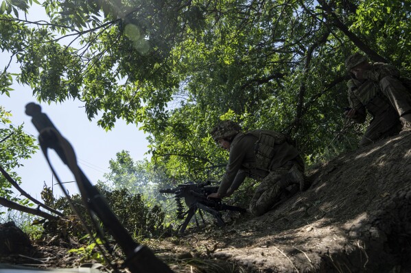 FILE - A Ukrainian marine of 35th brigade fires by automatic grenade launcher AGS-17 towards Russian positions on the outskirts of Avdiivka, Ukraine, on June 19, 2023. Ukrainian troops are under intense pressure from a determined Russian effort to storm the strategically important eastern Ukraine city of Avdiivka, officials say. Kyiv’s army is struggling with ammunition shortages as the Kremlin’s forces pursue a battlefield triumph around the two-year anniversary of Moscow’s full-scale invasion and ahead of a March presidential election in Russia. (AP Photo/Evgeniy Maloletka, File)