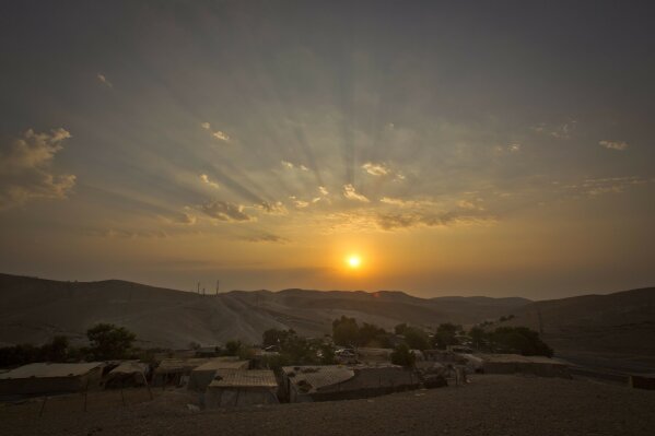 
              FILE - This Thursday, Sept. 13, 2018 file photo shows a sunrise over West Bank hamlet of Khan al-Ahmar. The Palestinian residents of Khan al-Ahmar cling to hopes that international pressure can save their strategically located West Bank hamlet from Israeli army bulldozers. After the West Bank hamlet lost its last legal protection against demolition late last week, Israeli forces could swoop in any day now to tear down the tiny desert community's few dozen shacks and schoolhouse made from recycled tires.(AP Photo/Majdi Mohammed)
            