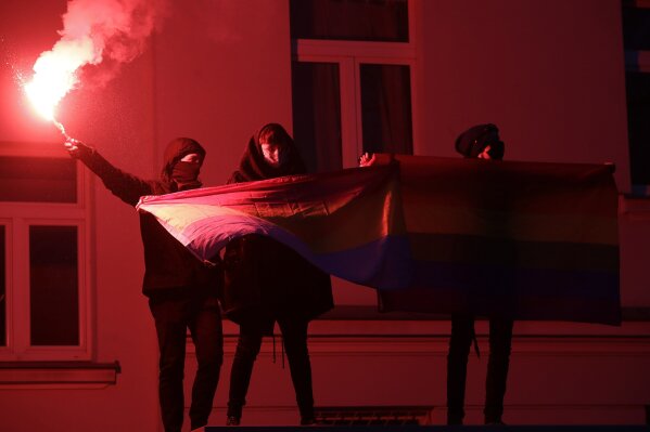 Polish protesters hold a flare and a rainbow flag during anti-government protests in Warsaw, Poland, Sunday Dec. 13, 2020. Thousands of protesters demonstrated in Warsaw in the latest large demonstration after a high court ruled in October to further tighten the country's already restrictive abortion law. Sunday's protest was scheduled to coincide with the 39th anniversary of the 1981 martial law crackdown by the country's communist regime. (AP Photo/Czarek Sokolowski)