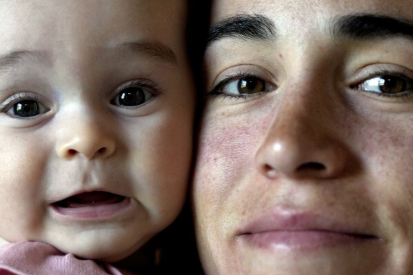 Belen Casetta holds her four-month-old daughter Lina at home in Pilar, Argentina, Monday, Oct. 9, 2023. Casetta will compete in the 3,000-meter steeplechase at the Pan American Games in Chile and will take her daughter with her to the games. (AP Photo/Natacha Pisarenko)