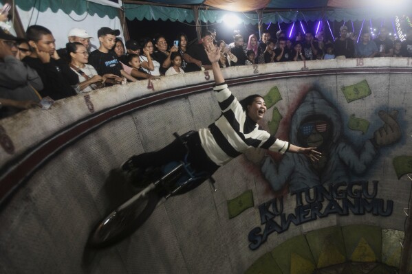 Sri Wahyuni, also known as Ayu, performs in the "wall of death", locally known as "tong setan" or satan's barrel, at a fairground in Medan, North Sumatra, Indonesia, Saturday, May 10, 2025. (AP Photo/Binsar Bakkara)
