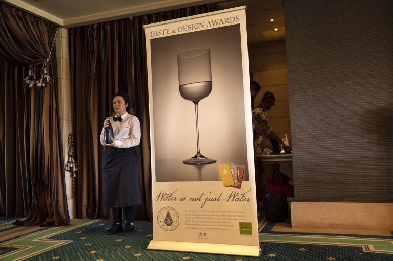 A waitress holds a bottle of water during an International Water Tasting Competition in Athens, Greece, on Wednesday, April 26, 2023. (AP Photo/Petros Giannakouris)