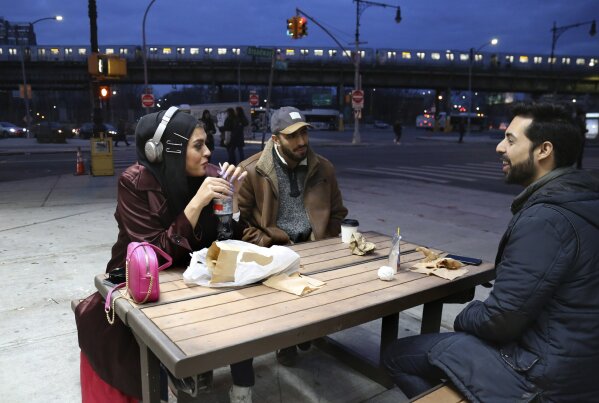 In this Dec. 27, 2019, photo, Amani Al-Khatahtbeh, founder of MuslimGirl.com, left, sips a soda while talking with old friends Mohammed Ali, right, and Saad Khan outside of a corner market in the Brooklyn borough of New York. Al-Khatahtbeh stays in New Jersey with her family when in town on business. Her home and office are in Los Angeles. Growing up, she remembers not having many friends and was often bullied. “High school kind of like made me into the person that I needed to be to create MuslimGirl,” she says. (AP Photo/Jessie Wardarski)
