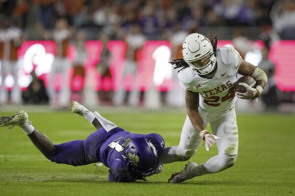Texas running back Jonathon Brooks (24) is pulled down by TCU safety Mark Perry (3) late in the fourth quarter of an NCAA college football game, Saturday, Nov. 11, 2023, in Fort Worth, Texas. Brooks did not return to the game after limping off the field. (Ricardo B. Brazziell/Austin American-Statesman via AP)