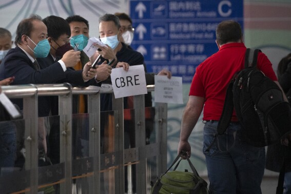 FILE - People wearing face masks wait at the international passenger arrivals area at Beijing Capital Inernational Airport in Beijing, on March 15, 2023. China announced Friday, Nov. 24, 2023 that it will allow visa-free entry for citizens of five European countries and Malaysia as it tries to encourage more people to visit for business and tourism. (AP Photo/Mark Schiefelbein, File)