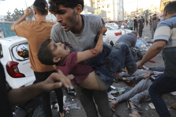FILE - An injured Palestinian boy is carried from the ground following an Israeli airstrike outside the entrance of the al-Shifa hospital in Gaza City, Friday, Nov. 3, 2023. Israel is sending top legal minds, including a Holocaust survivor, to The Hague this week to counter allegations that it is committing genocide against Palestinians in Gaza. (AP Photo/Abed Khaled, File)