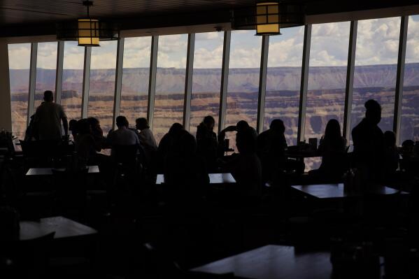 People eat at a restaurant overlooking the Grand Canyon Skywalk on Hualapai reservation Tuesday, Aug. 16, 2022, in northwestern Arizona. Roughly 600,000 tourists a year visit the Grand Canyon on the Hualapai reservation in northwestern Arizona — an operation that's the tribe's main source of revenue. (AP Photo/John Locher)
