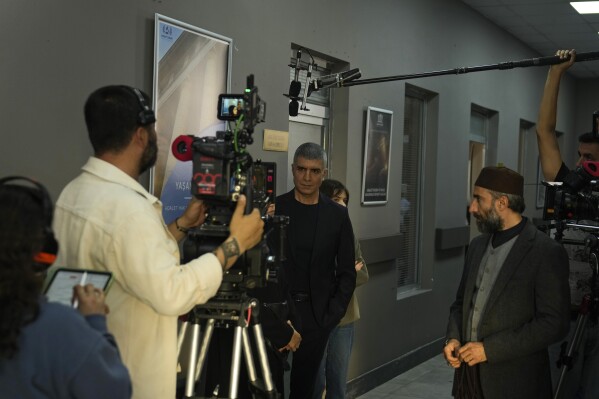 A production team is filming scenes of a Turkish drama with famous Turkish actor Ozcan Deniz, center, in Istanbul Turkey, Tuesday, April 30, 2024. (AP Photo/Khalil Hamra)