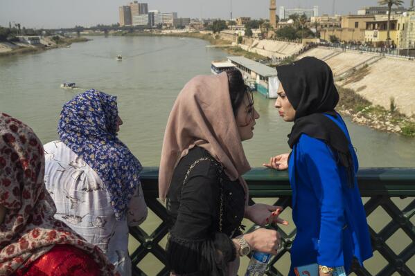 Women stand on the "martyrs' bridge" spanning the Tigris River in Baghdad, Iraq, Friday, Feb. 24, 2023. (AP Photo/Jerome Delay)