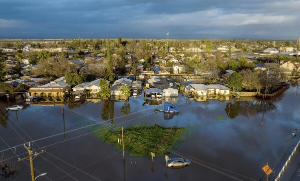 FILE - Following days of rain, floodwaters surround homes and vehicles in the Planada community of Merced County, Calif., Jan. 10, 2023. More Americans believe they've personally felt the impact of climate change because of recent extreme weather according to new polling from The Associated Press-NORC Center for Public Affairs Research. (AP Photo/Noah Berger, File)