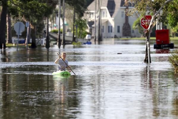 FILE - Halle Brooks kayaks down a street flooded by Hurricane Helene in the Shore Acres neighborhood Sept. 27, 2024, in St. Petersburg, Fla. (AP Photo/Mike Carlson, File)