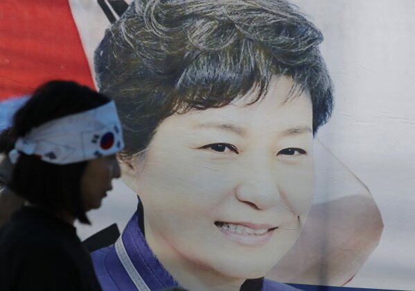 FILE - In this Aug. 29, 2019, file photo, a supporter of former South Korean President Park Geun-hye walks by the banner with her picture near the Supreme Court of Korea in Seoul, South Korea.  South Korea’s top court upheld 20-year prison term for Park over corruption on Thursday, Jan. 14, 2021. (AP Photo/Lee Jin-man, File)