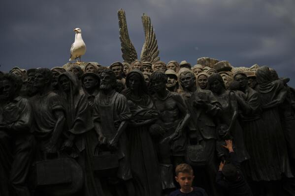 A young boy touches the "Angels Unaware" boat sculpture by Canadian artist Timothy P. Schmalz placed at St. Peter's square at the Vatican, Monday, April 28, 2025. (AP Photo/Francisco Seco)