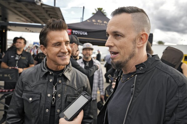 Scott Stapp, left, and Mark Tremonti, right, members of the rock band Creed, take part in an interview during an NASCAR Daytona 500 practice auto race Thursday, Feb. 15, 2024, at Daytona International Speedway in Daytona Beach, Fla. (AP Photo/Chris O'Meara)