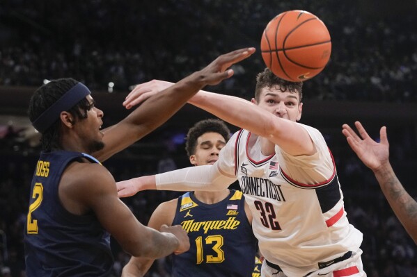 UConn center Donovan Clingan (32) and Marquette guard Chase Ross (2) fight for a loose ball during the first half of an NCAA college basketball game in the championship of the Big East Conference tournament, Saturday, March 16, 2024, in New York. (AP Photo/Mary Altaffer)