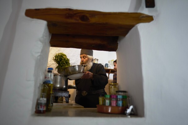 O monge cristão ortodoxo Padre Spyridon de Amorgos, cozinha na cozinha do Mosteiro de Panagia Hozoviotissa, na ilha de Amorgos, na segunda-feira, 24 de março de 2025. (AP Photo/Petros Giannakouris)