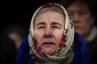 Olha Kosianchuk, 64, cries during a memorial service to mark the one-year anniversary of the start of the Russia Ukraine war, in Bucha, Ukraine, Friday, Feb. 24, 2023. Olha's husband was killed during the occupation of Bucha by Russian troops during the first weeks of the war. (AP Photo/Emilio Morenatti)