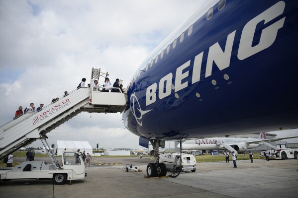 FILE - Visitors walk up the steps of the Boeing 777X airplane during the Paris Air Show in Le Bourget, north of Paris, France, Monday, June 19, 2023. Boeing deliveries of new airline jets slumped in the third quarter as the company struggled with production problems that are cutting into its ability to generate cash. Boeing said Tuesday, Oct. 10, 2023, that it delivered 27 planes in September, including 15 of its best-seller, the 737 Max. (AP Photo/Lewis Joly)