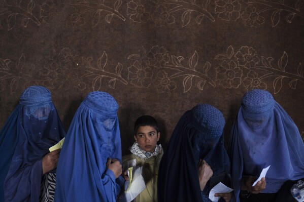 FILE - Afghan women wait to receive cash at a money distribution point organized by the World Food Program, in Kabul, Afghanistan, on Nov. 20, 2021. The United Nations has been forced to cut food, cash payments and assistance to millions of people in many countries because of “a crippling funding crisis” that has seen its donations plummet by about half as acute hunger is hitting record levels, a top official said Friday, July 28, 2023. (AP Photo/Petros Giannakouris, File)