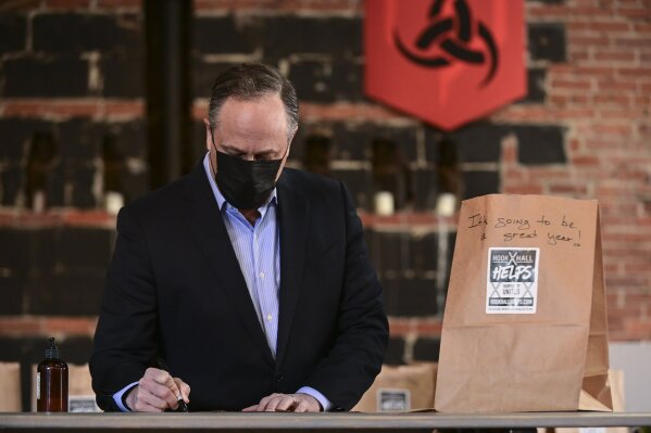Doug Emhoff, husband of Vice President Kamala Harris, writes messages on relief packages as they tour "Hook Hall Helps" a COVID-19 relief effort that organizes and distributes prepared meals and care kits to local hospitality workers whose jobs have been impacted by pandemic-related shutdowns and restrictions, during a visit to the organization in Washington, on Monday, March 8, 2021. (Erin Scott/Pool via AP)