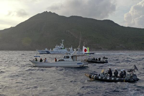 FILE - Japanese Coast Guard vessel and boats, rear and right, sail alongside a Japanese activists' fishing boat, center with a flag, near a group of disputed islands called Diaoyu by China and Senkaku by Japan, early Sunday, Aug. 18, 2013. Japan protested to Beijing after spotting Chinese and Russian warships just outside of Japanese territorial waters around the disputed East China Sea islands earlier Monday, July 4, 2022, prompting criticisms from China. (AP Photo/Emily Wang, File)
