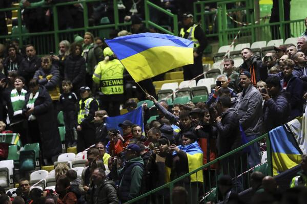 Spectators wave Ukrainian flag before the start of the Champions League Group F soccer match between Celtic and Shakhtar Donetsk at Celtic park, Glasgow, Scotland, Tuesday, Oct. 25, 2022. (AP Photo/Scott Heppell)