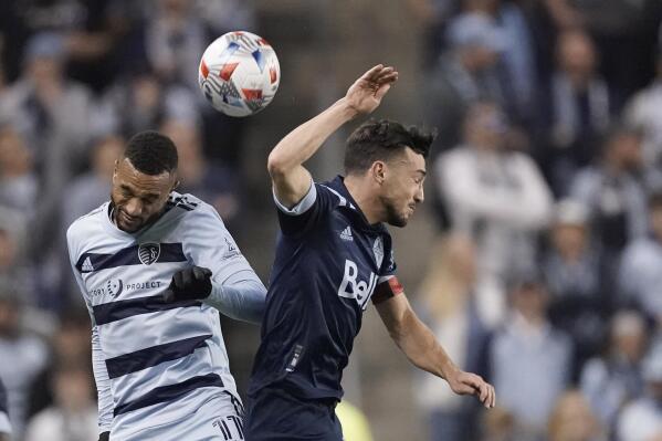 Sporting Kansas City forward Khiry Shelton, right, and Vancouver Whitecaps midfielder Russell Teibert, right, battle for the ball during the second half of an MLS soccer match, Saturday, Nov. 20, 2021, in Kansas City, Kan. Sporting KC won 3-1. (AP Photo/Charlie Riedel)