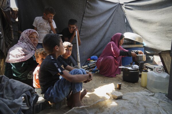 Tahreer Abu Jazar, 36, right, prepares an Eid al-Adha meal for her family inside their tent at a camp for displaced Palestinians in Mawasi Khan Younis, Gaza Strip, on Friday, June 6, 2025. (AP Photo/Abdel Kareem Hana)