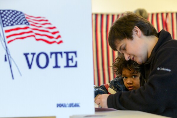 Levi Canon, 5, of Chesterfield, N.H., watches his mother, Bethany, fill out her ballot in the New Hampshire primary on Tuesday, Jan. 23, 2024. (Kristopher Radder /The Brattleboro Reformer via AP)