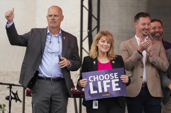 Ohio State Rep. Jennifer Gross, R-West Chester, holding a "Choose Life" sign, center, joined by Ohio State Rep. Adam Bird, R-New Richmond, left, and Ohio State Rep. Thomas Hall, R-Madison Township, right, stand together on stage during the Ohio March for Life rally at the Ohio State House in Columbus, Ohio, Oct. 6, 2023. The statewide battles over abortion rights that have erupted since the U.S. Supreme Court overturned a constitutional right to the procedure have exposed another fault line: commitment to democracy. (AP Photo/Carolyn Kaster)