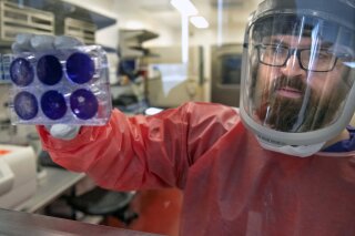 Matt Dunn, a researcher for the Center for Vaccine Research at the University of Pittsburgh, holds dead samples of the coronavirus (COVID-19), Thursday, Feb. 27, 2020, at the Biomedical Science Tower 3 in Oakland, Pa. (Nate Guidry/Pittsburgh Post-Gazette via AP)