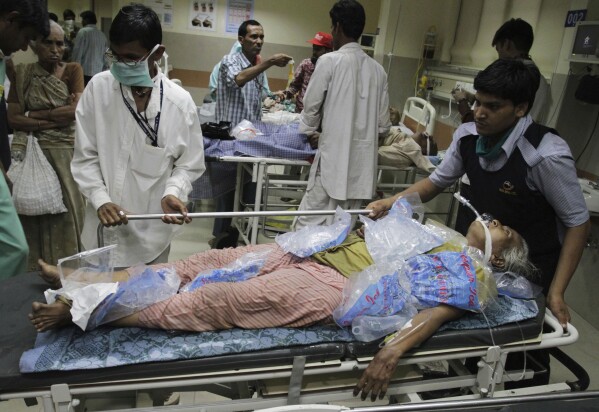People wheel in a heat stroke patient, covered in ice cube bags, at a hospital in Ahmadabad, India, May 21, 2010. (AP Photo/Ajit Solanki, File)