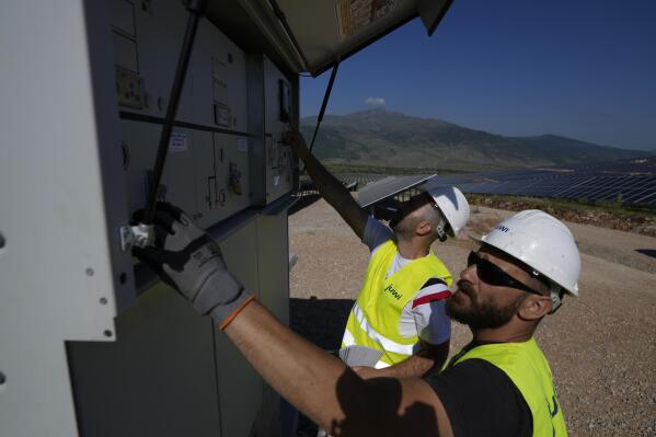 FILE - Maintenance engineers check installations at a new solar park outside the northern Greek city of Kozani on June 3, 2022. A new report has found that clean energy now provides more employment than the fossil fuel industry, reflecting the shift that efforts to tackle climate change are having on the global jobs market. (AP Photo/Thanassis Stavrakis, File)