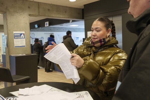 A woman reads her ballot during an early voting for Greenlandic parliamentary elections at the city hall in Nuuk, Greenland, Monday, March 10, 2025. (AP Photo/Evgeniy Maloletka)