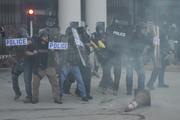Law enforcement officers gather as tear gas fills the air during a protest after federal immigration authorities conducted an operation on Friday, June 6, 2025, in Los Angeles. (AP Photo/Jae C. Hong)