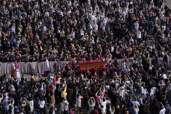 The ceremony with the Pope Francis' body, who will lie in state at St. Peter's Basilica for three days, pass through the crowd at the Vatican, Wednesday, April 23, 2025. (AP Photo/Gregorio Borgia)