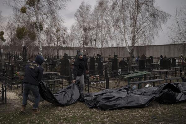 Workers carry the body of people found dead to a cemetery in Bucha, outskirts of Kyiv, Ukraine, Tuesday, April 5, 2022. Ukraine’s president told the U.N. Security Council on Tuesday that the Russian military must be brought to justice immediately for war crimes, accusing invading troops of the worst atrocities since World War II. He stressed that Bucha was only one place and there are more with similar horrors. (AP Photo/Felipe Dana)