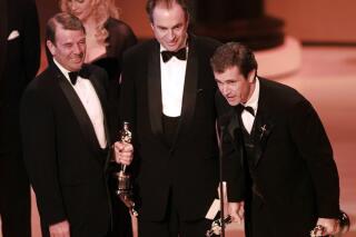 FILE - Mel Gibson, right, accepts the award for Best Picture for "Braveheart" at the 68th Annual Academy Awards in Los Angeles, Monday, March 25, 1996. Looking on are co-producers Alan Ladd Jr., left, and Bruce Davey. (AP Photo/Eric Draper, File)