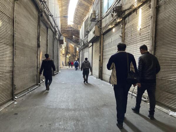People walk through closed shops of Tehran's Grand Bazaar, Iran, Tuesday, Nov. 15, 2022. Many shops at Grand Bazaar in Iran's capital city were closed Tuesday amid strike calls following the September death of a woman who was arrested by the country's morality police. (AP Photo/Vahid Salemi)