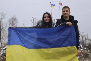 In this photo provided by the Ukrainian Presidential Press Office, Ukrainian teenager Bohdan Yermokhin, right, holds the Ukraine flag on the Ukraine-Belarus border in Ukraine, Sunday, Nov. 19, 2023. The orphaned Ukrainian teenager was taken to Russia last year during the war in his country and has now returned home after being reunited with relatives in Belarus on his 18th birthday Sunday. (Ukrainian Presidential Press Office via AP)