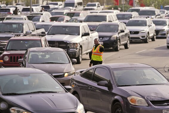 FILE - An officer directs traffic at Love Field Airport in Dallas, Wednesday, Dec. 21, 2022. The rate of people working from home dropped from 17.9% in 2021 to 15.2% in 2022, according to new survey data released Thursday, Sept. 14, 2023, by the U.S. Census Bureau on life in America, covering commuting times internet access, family life, income, education levels, disabilities, military service and employment. (AP Photo/LM Otero, File)