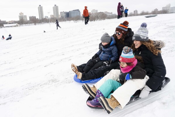 Allison Melowsky and wife Sarah Melowsky sled down Cricket Hill with their kids Parker, 7, and Zane, 4, in the Uptown neighborhood after a major snowstorm hit the Chicago area, Saturday, Jan. 13, 2024. (Pat Nabong /Chicago Sun-Times via AP)