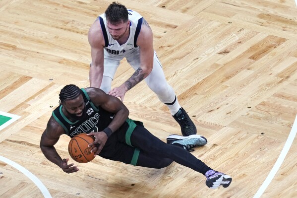 Boston Celtics guard Jaylen Brown, bottom, hits the floor while pressured by Dallas Mavericks guard Luka Doncic, top, during the first half of Game 2 of the NBA Finals basketball series, Sunday, June 9, 2024, in Boston. (AP Photo/Michael Dwyer)