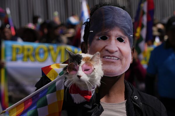 A man wearing a mask depicting former President Evo Morales marches with his cat towards the offices of the Electoral Tribunal in El Alto, Bolivia, Friday, May 16, 2025. (AP Photo/Juan Karita)