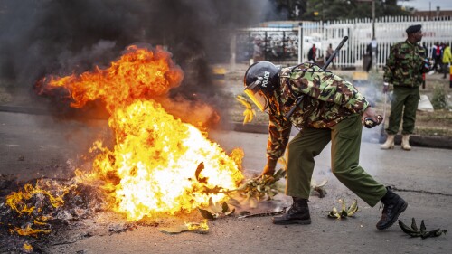 A police officer tries to put out a burning barricade erected by demonstrators during protests in the capital Nairobi, Kenya Friday, July 7, 2023. Dozens of anti-government protesters were arrested in Nairobi on Friday as other parts of the country also witnessed demonstrations called by the opposition against newly imposed taxes and the cost of living. (AP Photo/Samson Otieno)