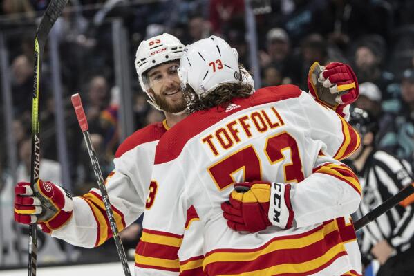 Calgary Flames, including, defenseman Noah Hanifin, left, and forward Tyler Toffoli celebrate and empty-net short-handed goal during the third period of an NHL hockey game against the Seattle Kraken, Saturday, April 9, 2022, in Seattle. The Flames won 4-1. (AP Photo/Stephen Brashear)